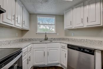A kitchen with white cabinets and a granite countertop.